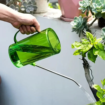 Arrosoir vert en plastique avec bec long en inox, arrosant une plante verte en pot