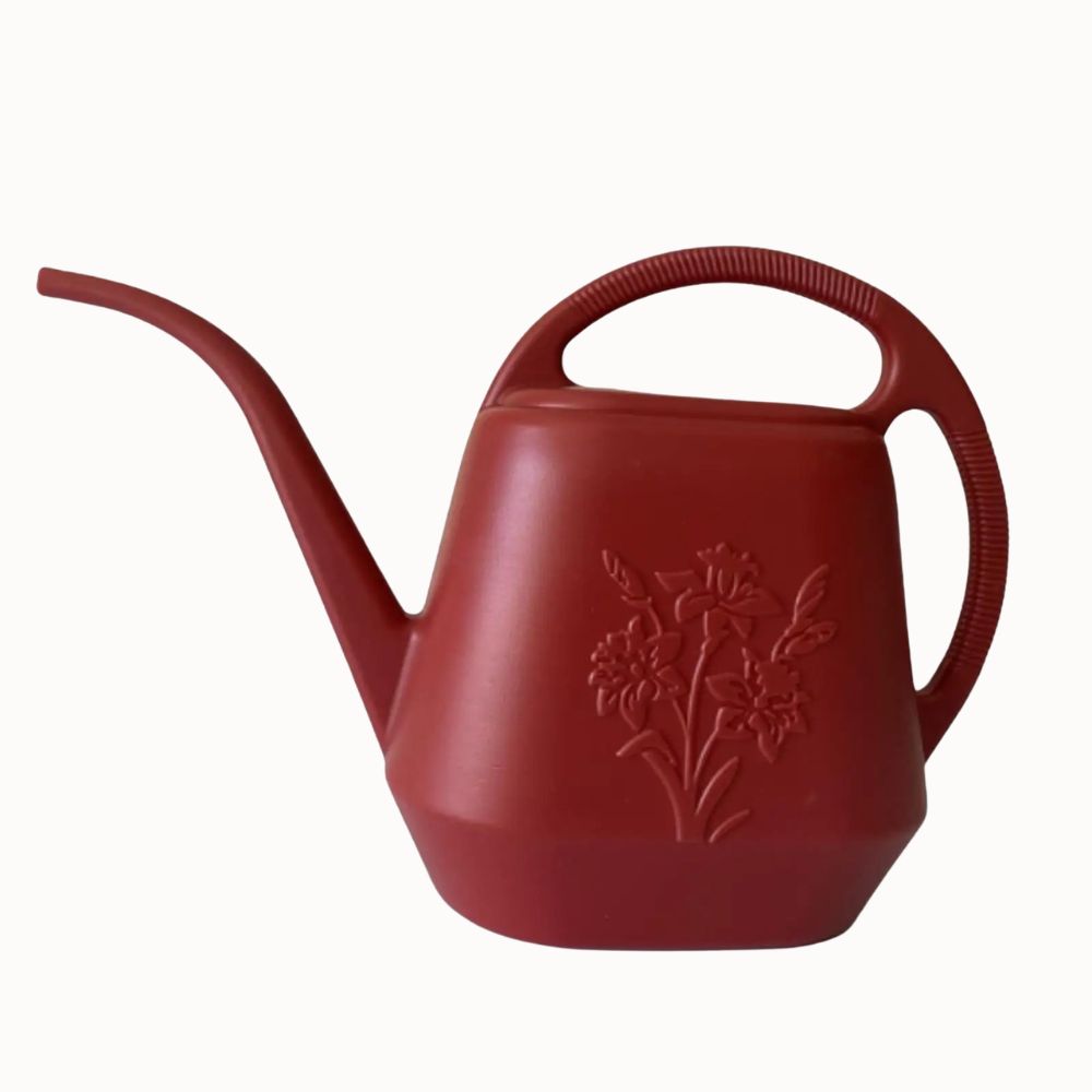 Arrosoir en plastique rouge avec long bec, motif floral en relief et poignée ergonomique