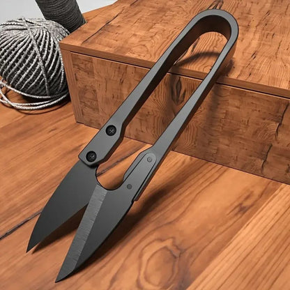 Sécateur noir en métal avec lames en U sur une table en bois clair et décor naturel