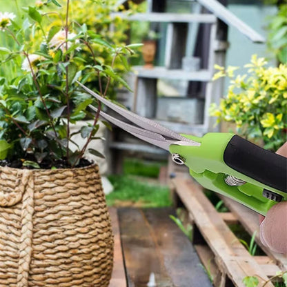 Main en train de tenir un sécateur vert, taillant une plante à l'intérieur d'un jardin