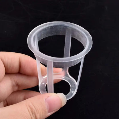 Un godet transparent en plastique avec des ouvertures pour la culture hydroponique, tenu par une main