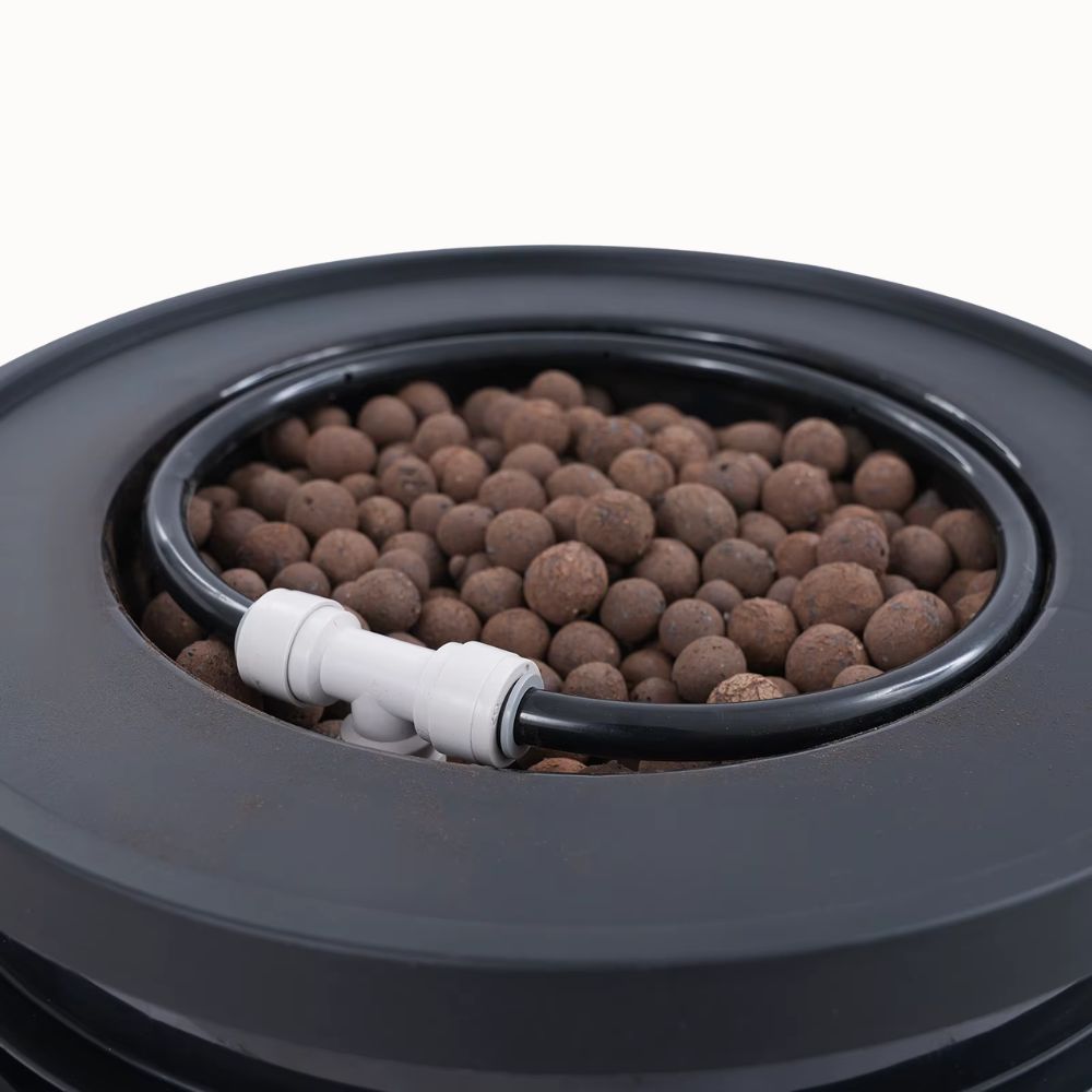 Système hydroponique avec billes d'argile et tuyaux noirs sur un fond clair