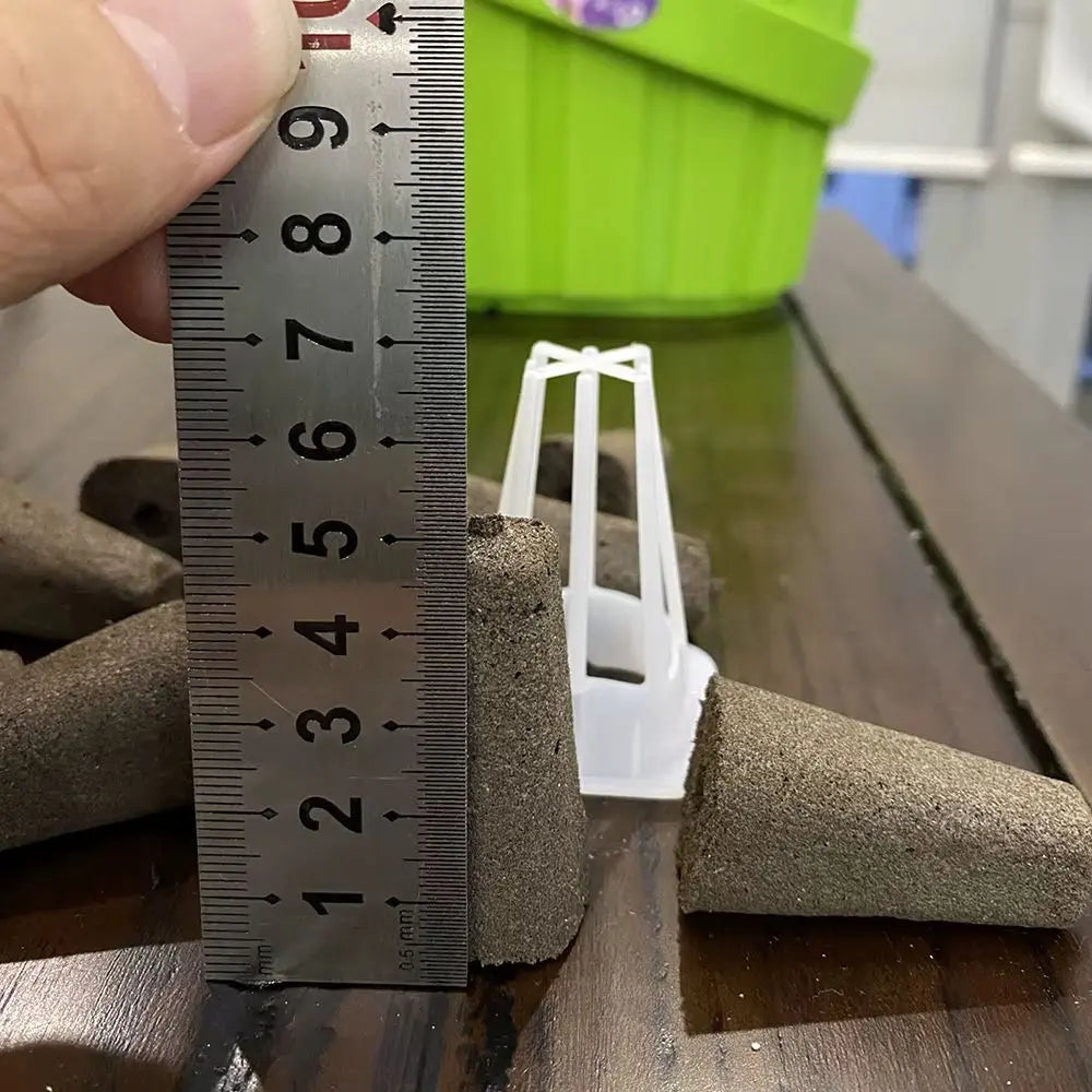 Main en tenant une règle à côté de mousse de culture et d'un support blanc sur une table en bois