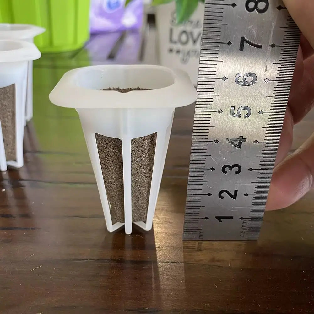 Des pots en plastique blanc avec de la mousse et de la terre, mesurés avec une règle en métal