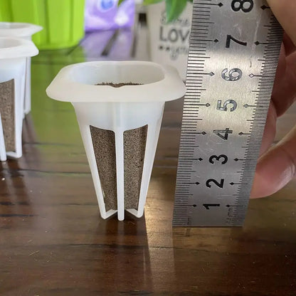 Des pots en plastique blanc avec de la mousse et de la terre, mesurés avec une règle en métal