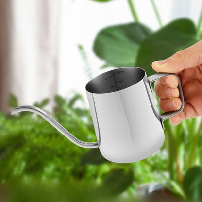 Arrosoir en métal argenté avec bec de précision, tenu par une main, sur fond de plantes vertes