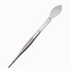 Pince-spatule en métal argenté avec une partie plate et une partie courbée, surface lisse et brillante