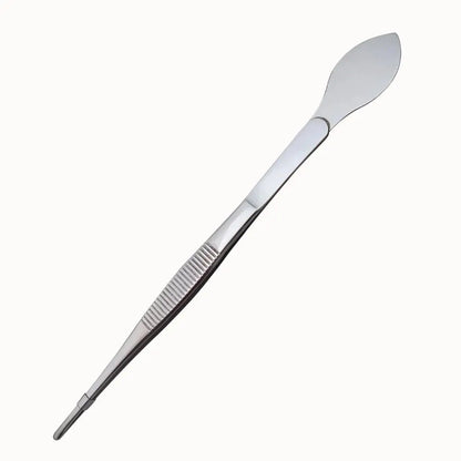 Pince-spatule en métal argenté avec une partie plate et une partie courbée, surface lisse et brillante