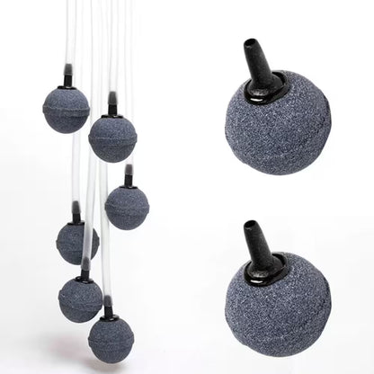Cinq pierres à air rondes grises avec tuyaux noirs pour oxygénation dans un décor minimaliste