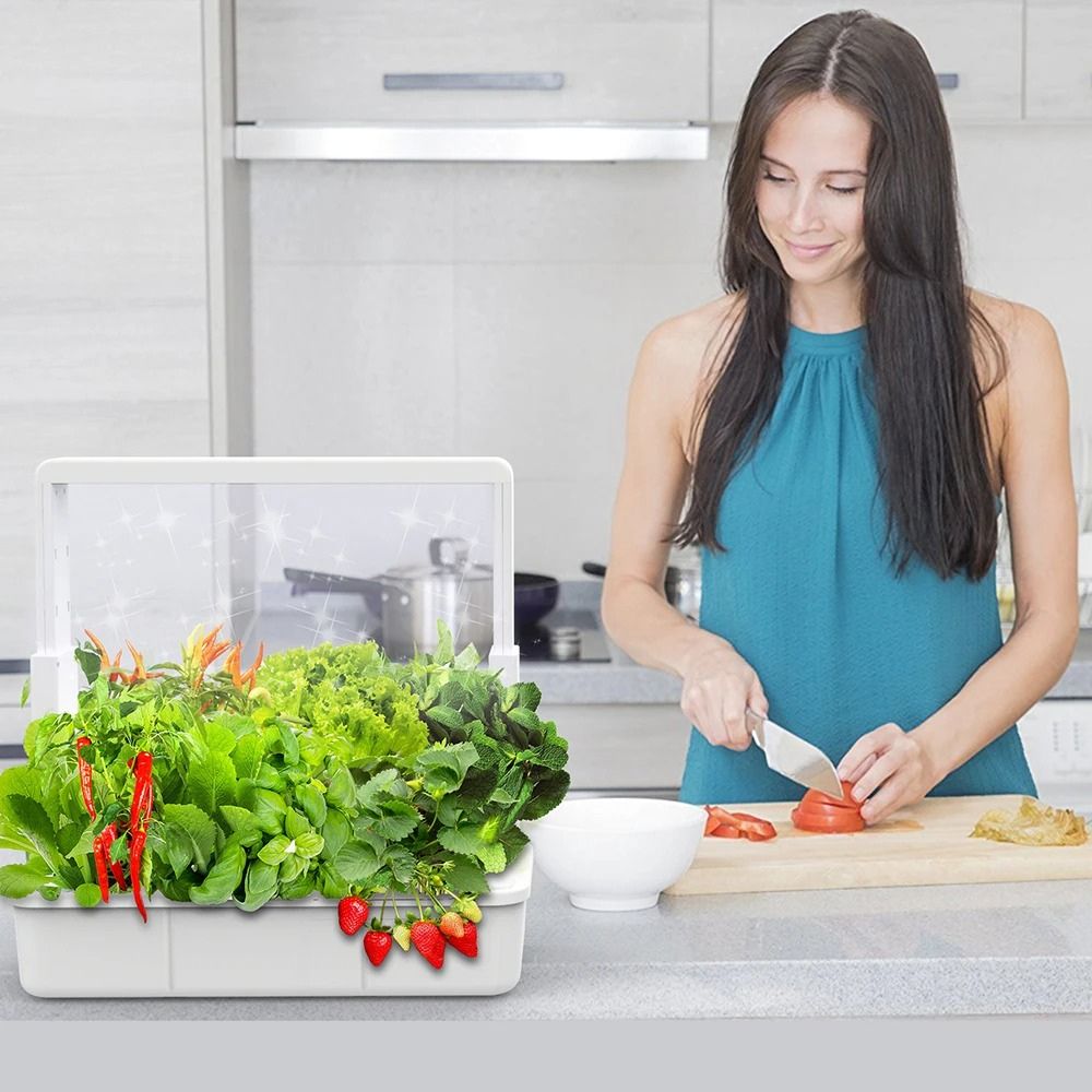 Femme préparant des légumes frais devant un potager d'intérieur rempli de plantes vertes et rouges