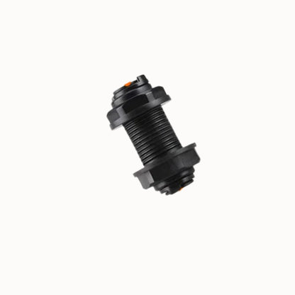 Raccord traversant de paroi en plastique noir avec filetage et joint orange visible sur l'image