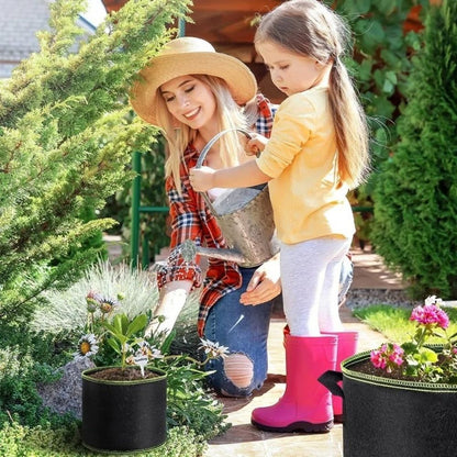 Femme avec un chapeau arrosant des plantes dans un pot noir, enfant en bottes roses à côté