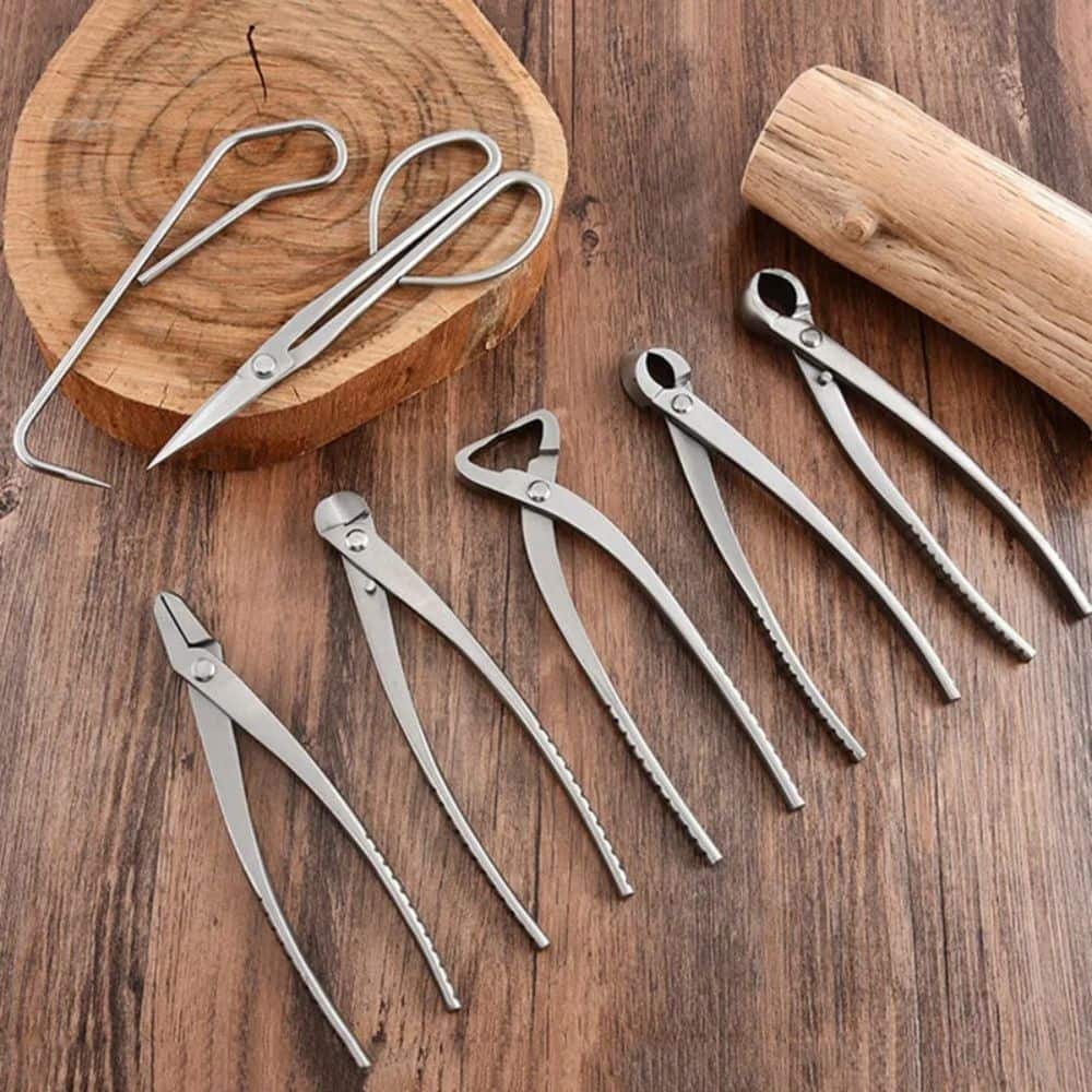 Outils de jardinage en métal argenté disposés sur une surface en bois avec un rondin en arrière-plan