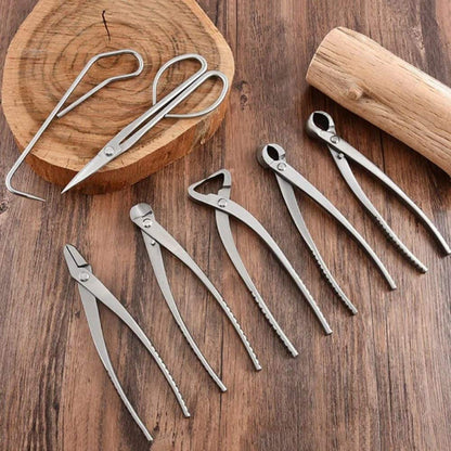 Outils de jardinage en métal argenté disposés sur une surface en bois avec un rondin en arrière-plan