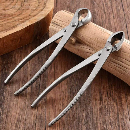 Deux sécateurs en métal argenté posés sur une surface en bois, avec un design élégant et des poignées ergonomiques