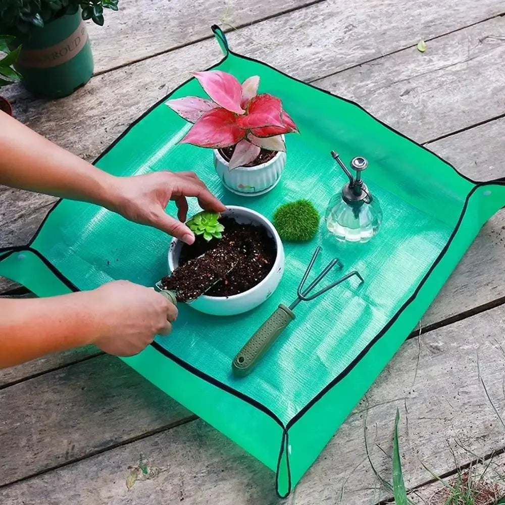 Tapis de rempotage vert avec des pots de fleurs, terreau, outils de jardinage et une bouteille d'eau