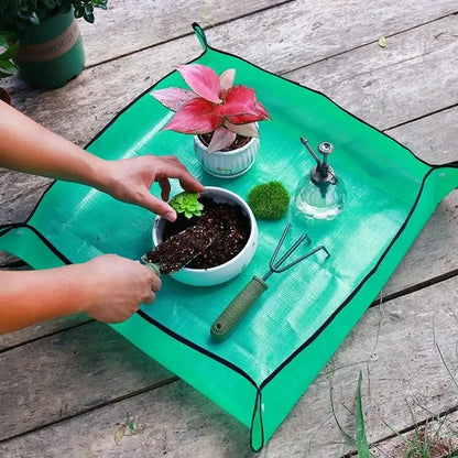 Tapis de rempotage vert avec des pots de fleurs, terreau, outils de jardinage et une bouteille d'eau