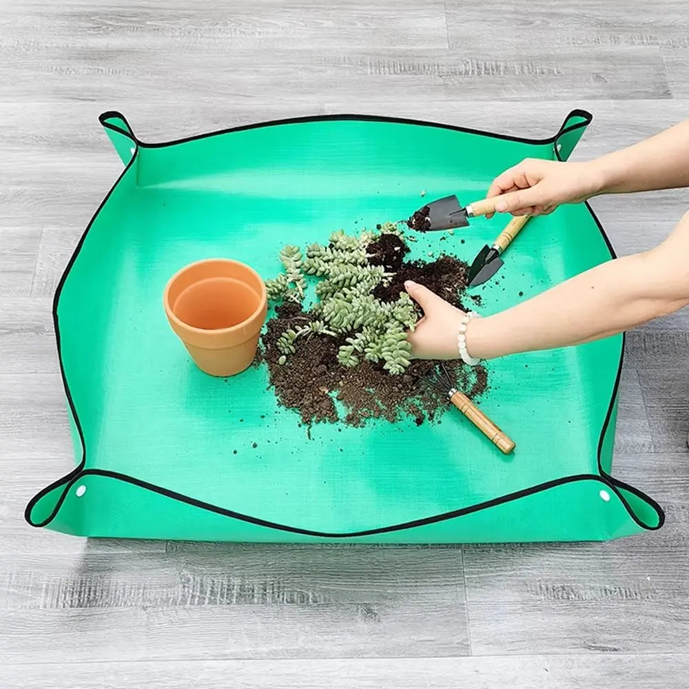 Plan de travail étanche vert avec des plantes, un pot en terre cuite et des outils de jardinage