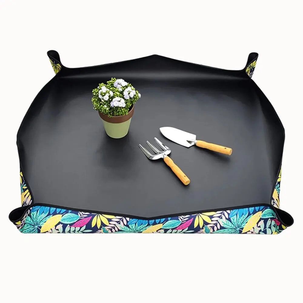 Tapis de rempotage noir avec motifs colorés, pot de fleurs et outils de jardinage en bois sur le dessus