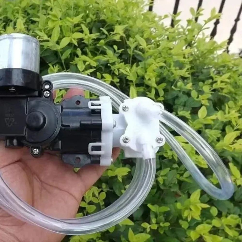 Main tenant une mini pompe à eau automatique avec tuyau transparent et éléments en plastique noir et blanc